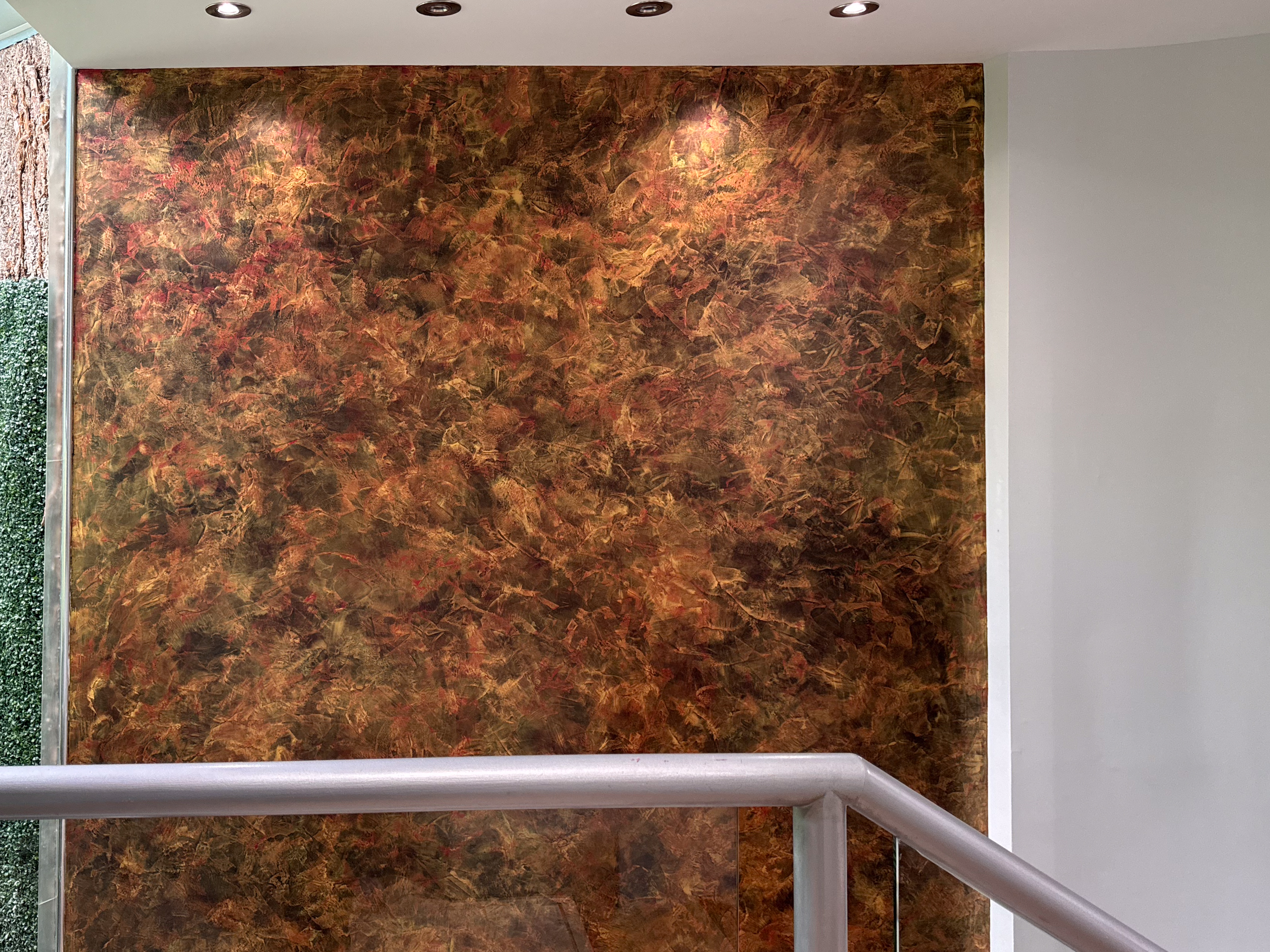 A dramatic grand stairway accent wall featuring black, red, and gold venetian plaster walls in a luxury Toronto home by Shane Baghai Development.