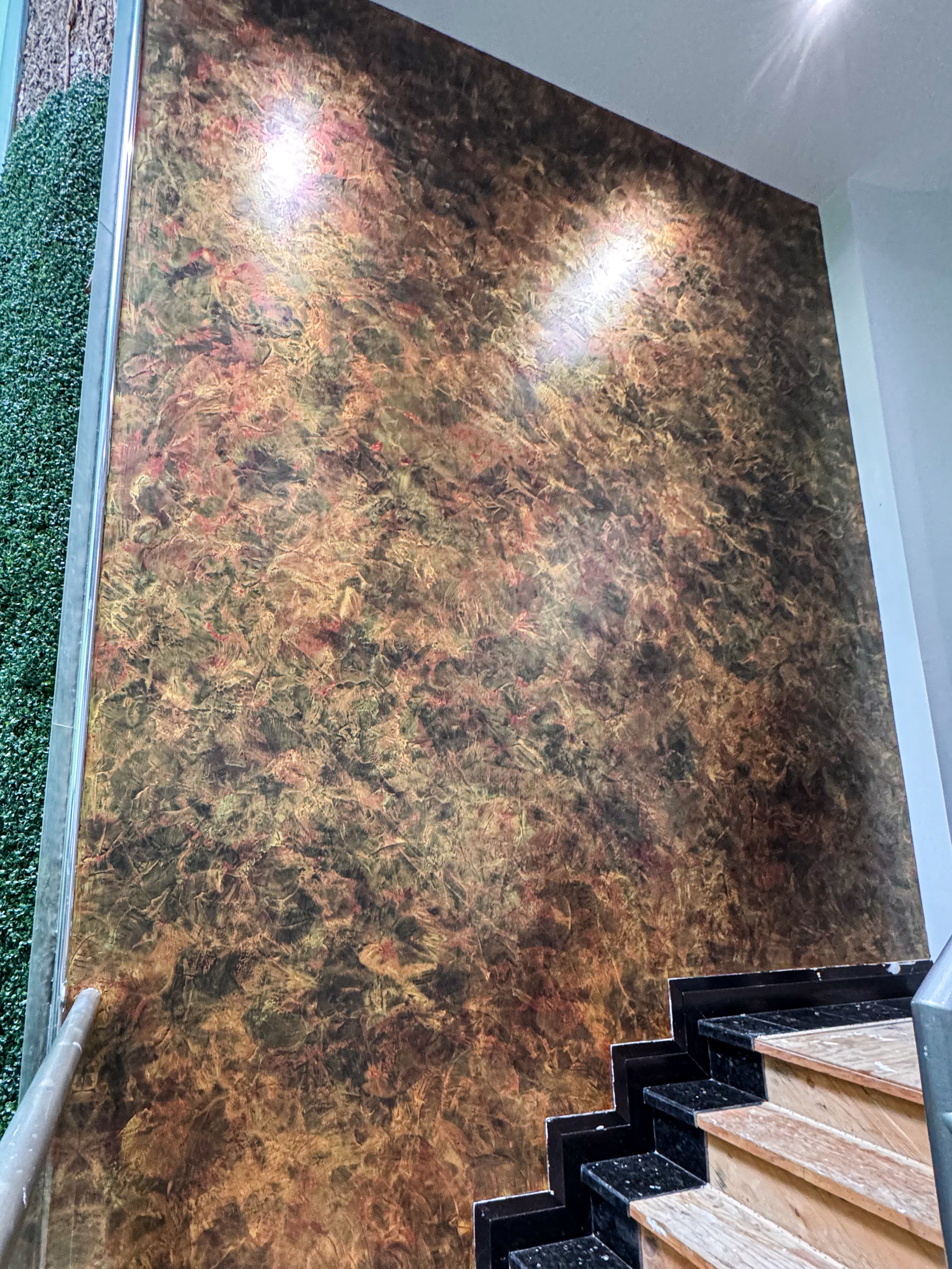 A dramatic grand stairway accent wall featuring black, red, and gold venetian plaster walls in a luxury Toronto home by Shane Baghai Development.