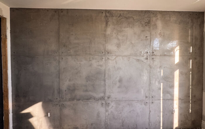 Custom concrete texture wall detailing using architectural vinyl sheet over fresh microcement plaster.