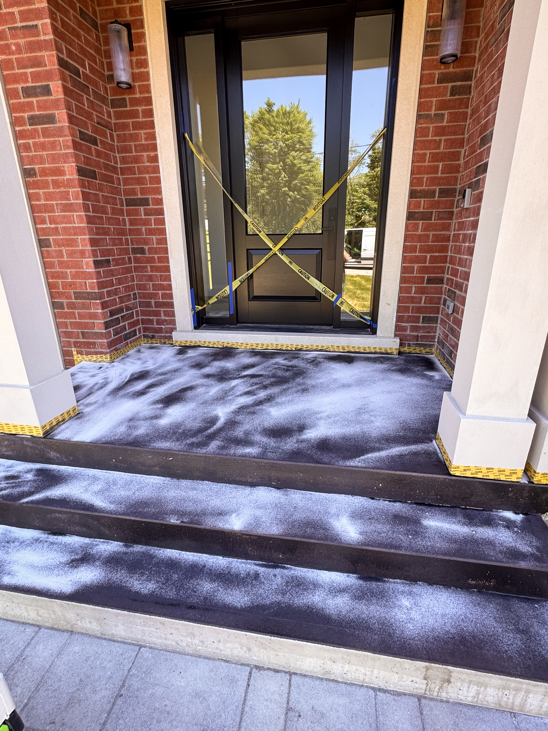 exterior-microcement-prep-epoxy-primer-sand-broadcast n exterior concrete porch being treated with a clear epoxy primer and broadcasted with silica sand to create a gritty, high-adhesion substrate.