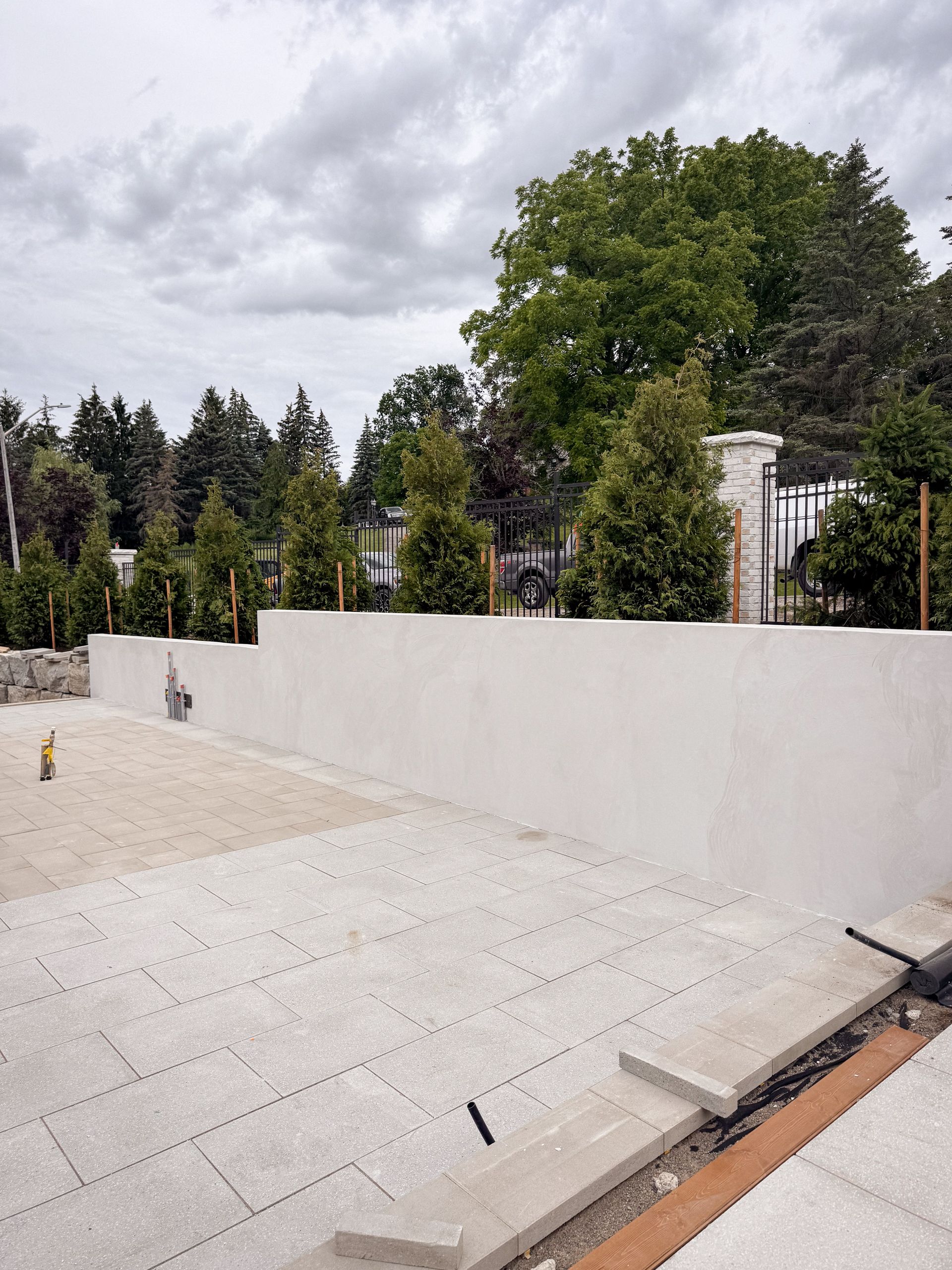 white-exterior-microcement-planters-kleinburg-toronto-3 During: Close-up of a modern outdoor garden in Kleinburg featuring vertical planters and architectural facades finished in a seamless, soft grey exterior microcement over a concrete base, surrounded by manicured landscaping.
