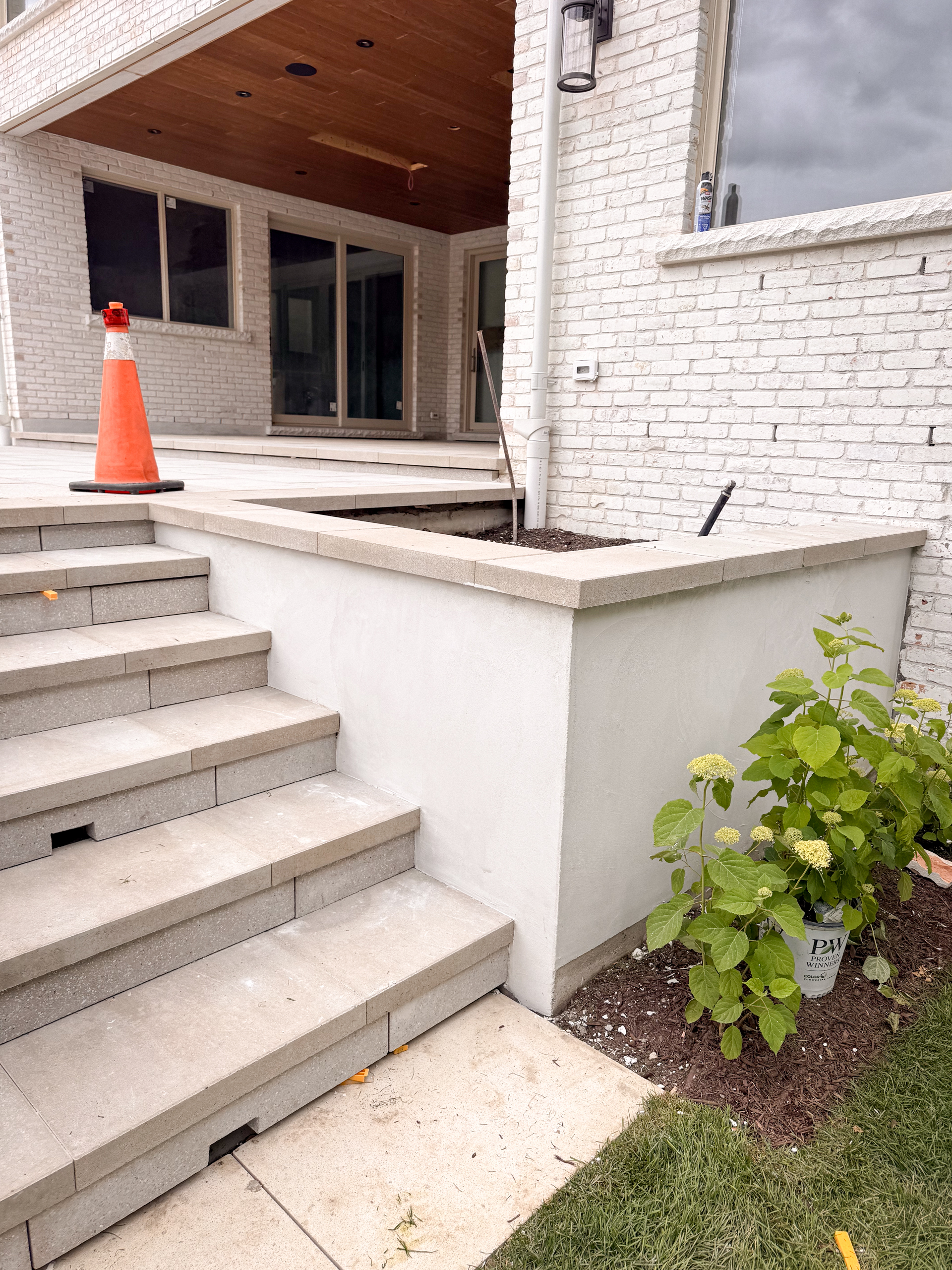 white-exterior-microcement-planters-kleinburg-toronto Close-up of a modern outdoor garden in Kleinburg featuring vertical planters and architectural facades finished in a seamless, soft grey exterior microcement over a concrete base, surrounded by manicured landscaping.