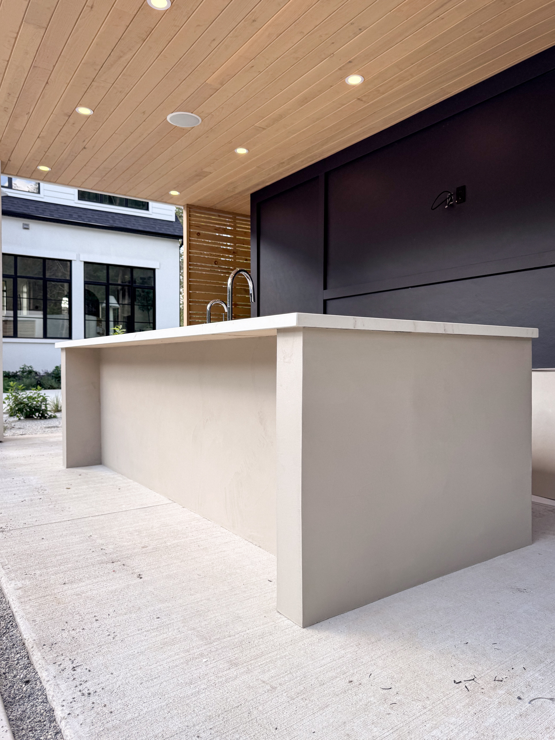 outdoor-microcement-kitchen-cabinet-erin-toronto-5 A luxury modern outdoor kitchen in Erin, Ontario, featuring a seamless greige microcement island with integrated cabinet doors and a sleek porcelain countertop.