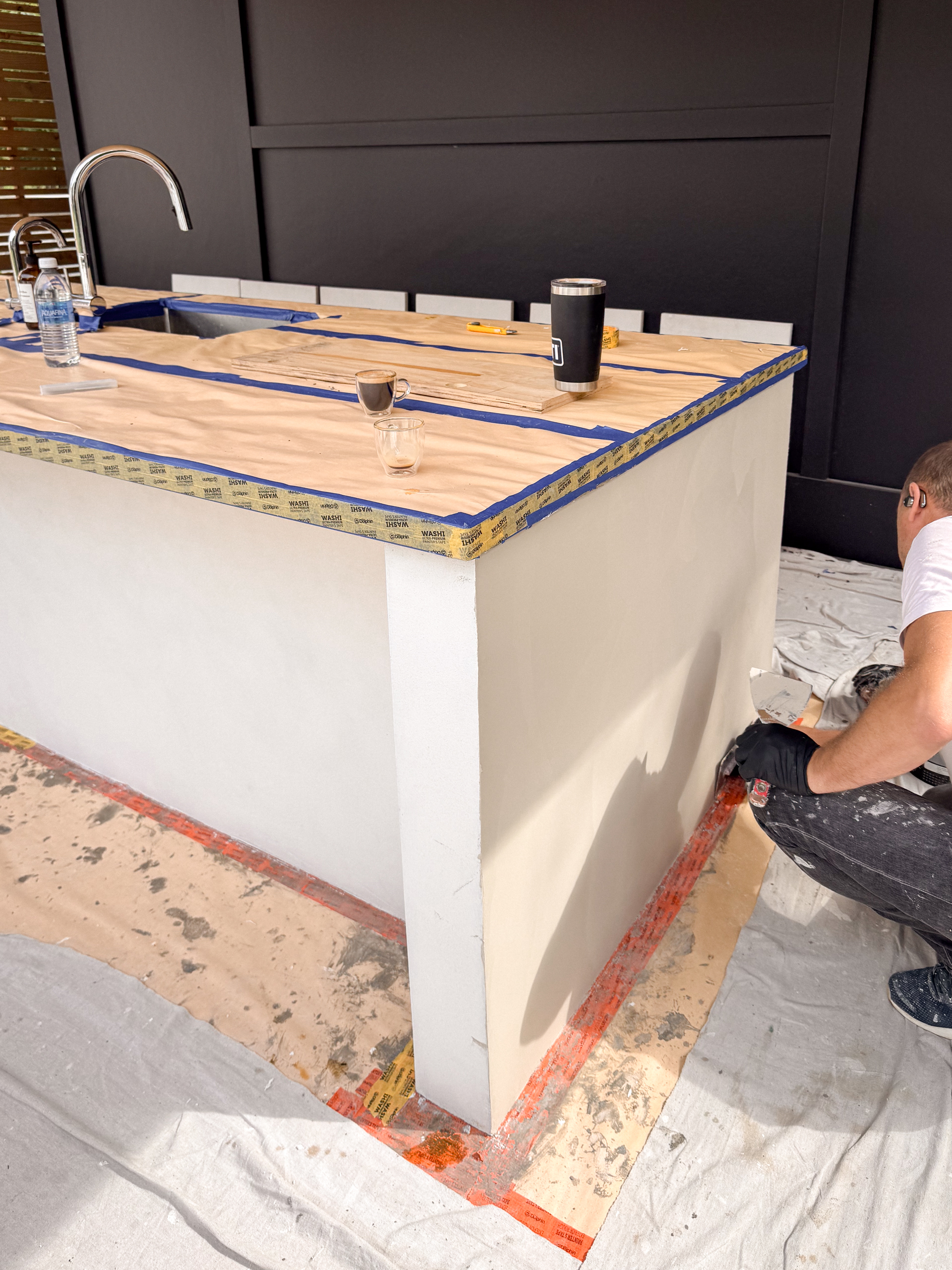 outdoor-microcement-kitchen-cabinet-erin-toronto-8 Chromatist artisan hand-applying a wet coat of greige microcement onto an outdoor kitchen structure using a professional trowel.