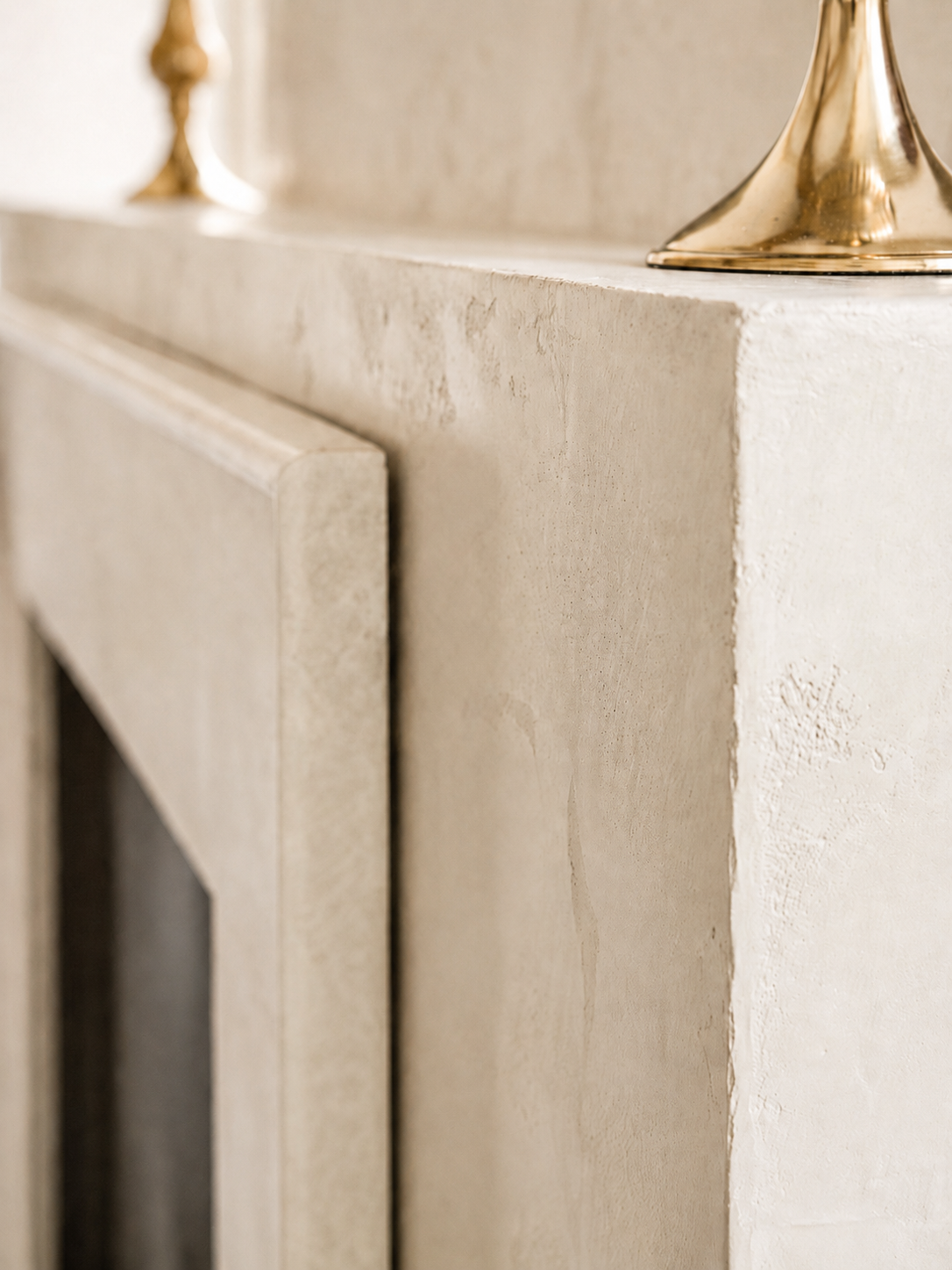 venetian-plaster-fireplace-world-map-design-master-bedroom6 Close-up of taupe Venetian plaster fireplace edge beside a creamy white natural stone surround