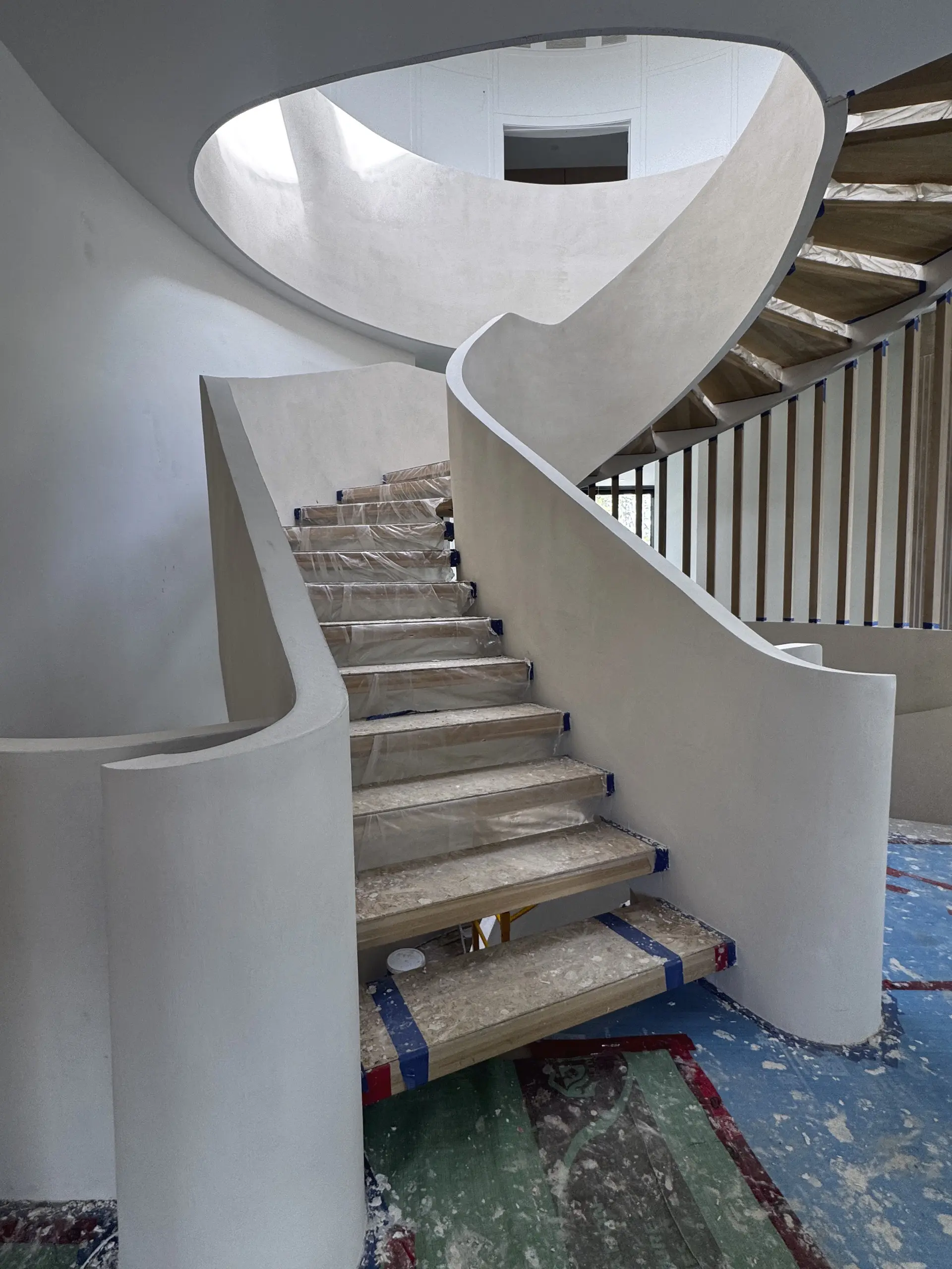 Finished curved microcement staircase in Richmond Hill with three levels and natural wood treads.