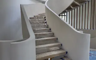 Finished three-level spiral microcement staircase in Richmond Hill with a curved mineral-finish skirt and retained wood treads.