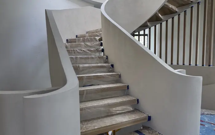 Finished three-level spiral microcement staircase in Richmond Hill with a curved mineral-finish skirt and retained wood treads.