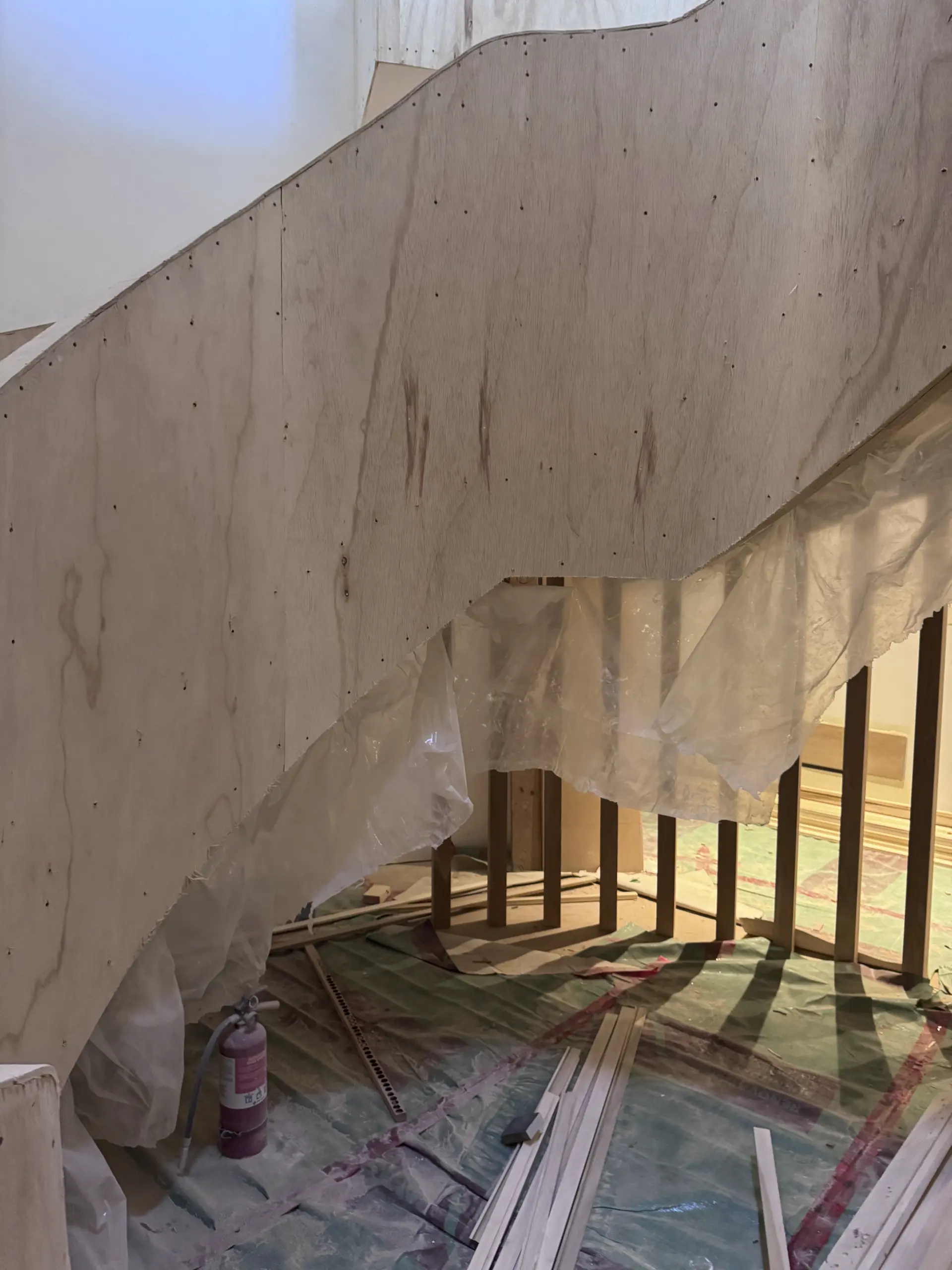 Hand-trowelled microcement being applied to the curved MDF skirt of a three-level spiral staircase.