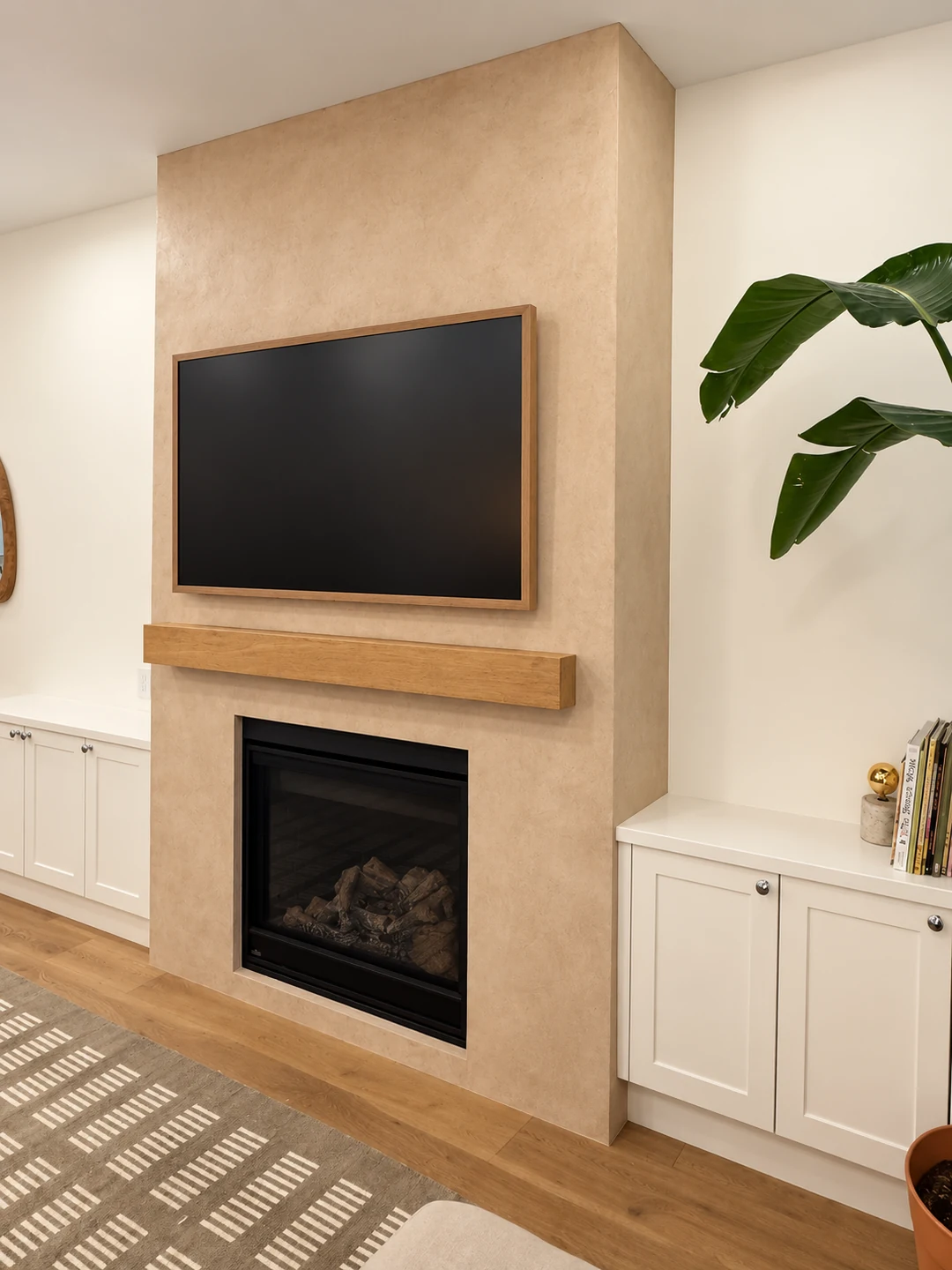Angled view of a warm taupe microcement fireplace surround in High Park, Toronto.