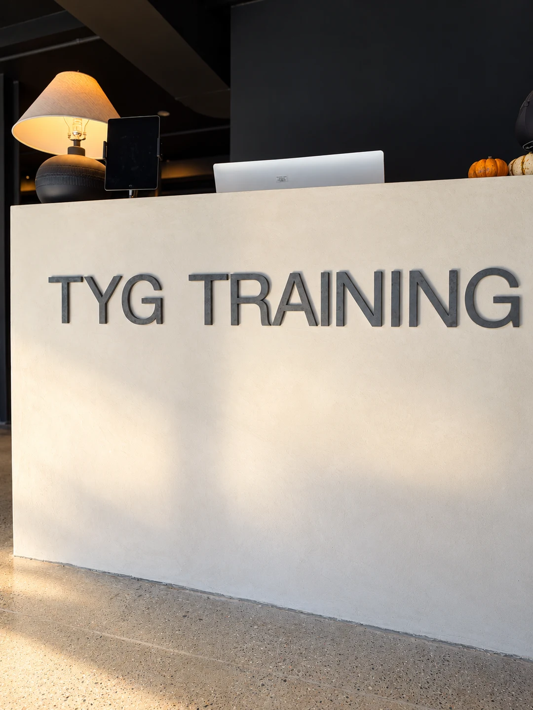 Pale microcement reception signage detail in a Toronto gym lobby