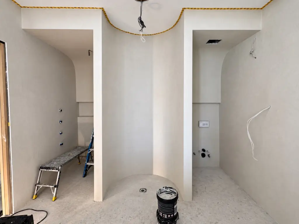 In-progress Toronto bathroom showing prepared shower zones before microcement finish layers are completed.
