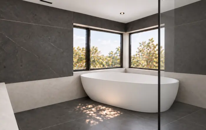 Freestanding tub beside charcoal shower walls and light greige microcement surfaces in a North York bathroom.