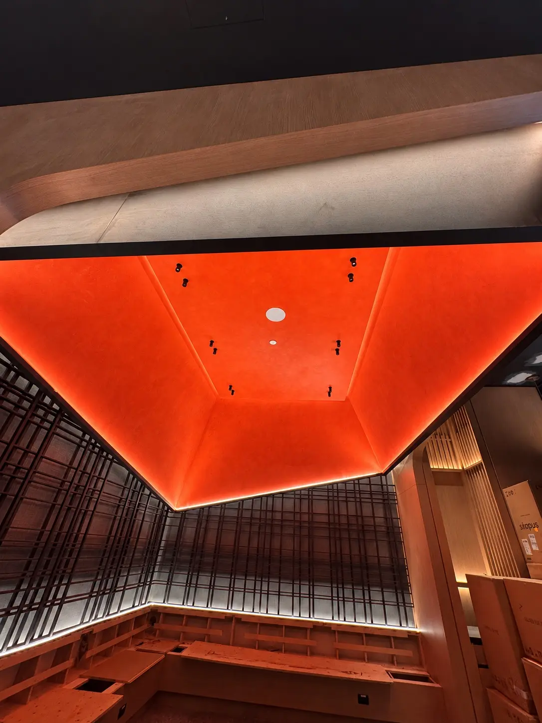 Finished Red Limewash Dropped Ceiling in Toronto Wide view of a finished red limewash dropped ceiling, with the ceiling plane framed by dark wall detailing and warm wood in a Toronto restaurant interior.